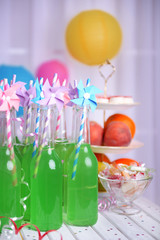 Bottles of drink with straw and fruits on decorative background