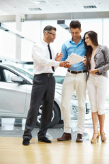 Young Couple Signing a Contract  in Car Showroom.