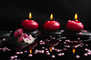 spa still life of red candles, zen stones with drops, orchid cam