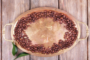 Coffee beans on metal tray on wooden background