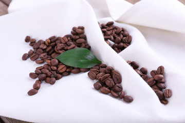 Coffee beans on white napkin on wooden background