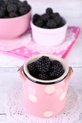 Fototapeta na wymiar Sweet blackberries in color bowl on bright background