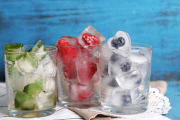 Ice cubes with mint leaves, raspberry and blueberry in glasses,