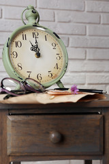 Naklejka premium Retro clock and glasses on table in room