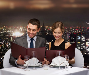 smiling couple with menus at restaurant