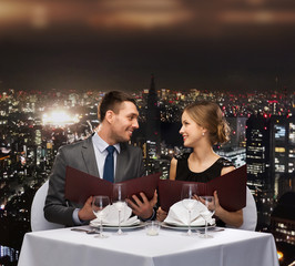 smiling couple with menus at restaurant