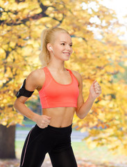 Fototapeta premium sporty woman running with smartphone and earphones