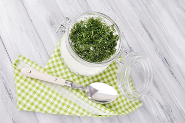 Glass round bowl of cream with a tuft of dill and pepper near