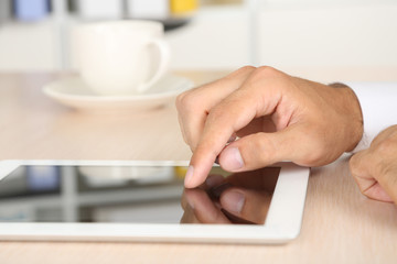 Man working on tablet on wooden background closeup