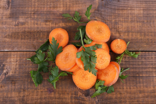 Slices of carrot and parsley on wooden background