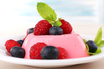 Heart shaped cake with berries on plate on wooden background