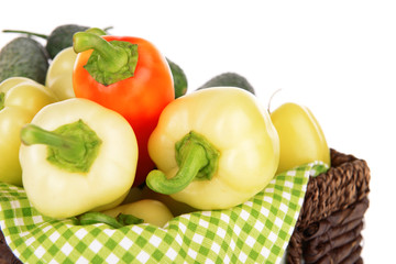 Yellow peppers with cucumbers in basket isolated on white