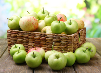Ripe apples in basket on table on natural background