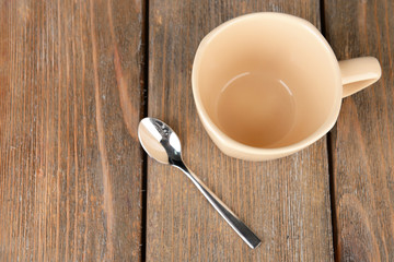 Empty cup with tea spoon on wooden background