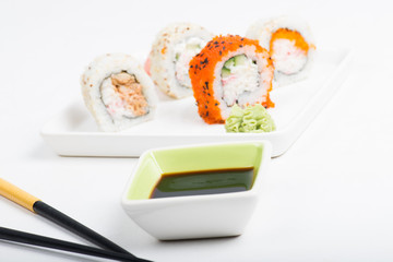 Focus on soy sauce, shushi rolls in back