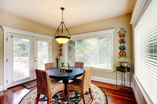 Dining Room With Round Black Table And Wicker Chairs