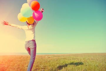 young asian woman on green grassland with colored balloons 