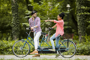Young couple riding on the tandem bicycle