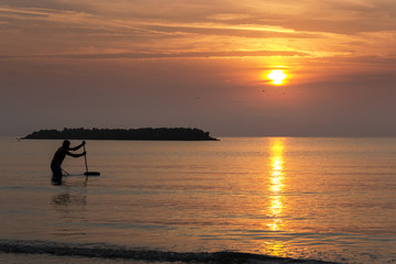 Fishing man in the sea during the sunrise