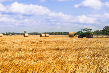 Fototapeta premium Tractor hauling bale of hay