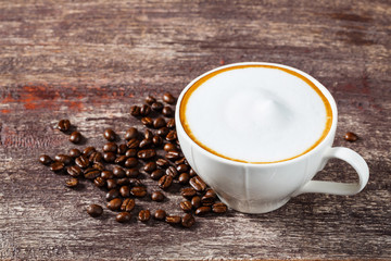 Cup of coffee and roasted bean on old wooden table