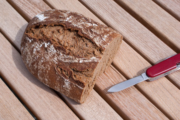 Rye bread laying with knife on the old wood table.