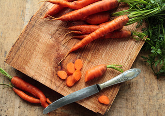 Fresh carrots on a kitchen cutting board with a knife