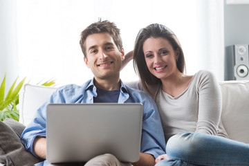 Couple relaxing on sofa with laptop