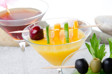 Orange, cherry and green vegetables cocktails on a beach environ