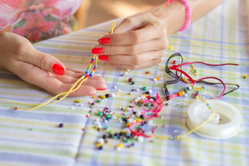 Naklejka premium Making bracelet of colorful beads