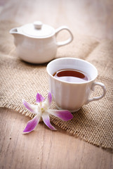 cup of black coffee  with purple orchid and burlap cloth on wood