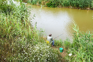 fisherman is fishing on riverbank