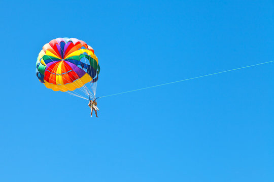people parascending on parachute in blue sky