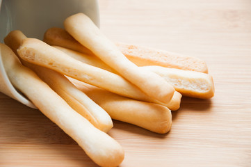 Breadsticks in napkin on wooden background.