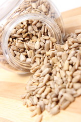 Heap of sunflower seeds in glass jar on wooden cutting board