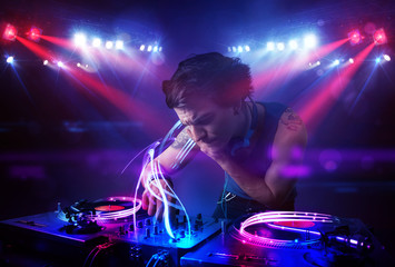 Fototapeta na wymiar Disc jockey playing music with light beam effects on stage