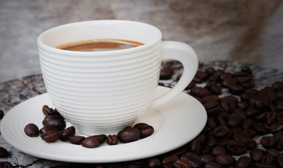 White cup in coffee beans, closeup