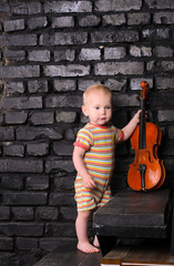 little boy with violin on brick wall background for text music