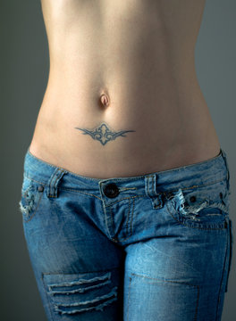 Flat female belly with tattoo in jeans