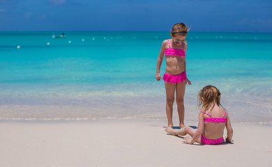 Naklejka premium Little cute girls walking on white beach during vacation