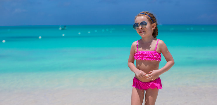 Cute little girl in sunglasses at beach during summer vacation