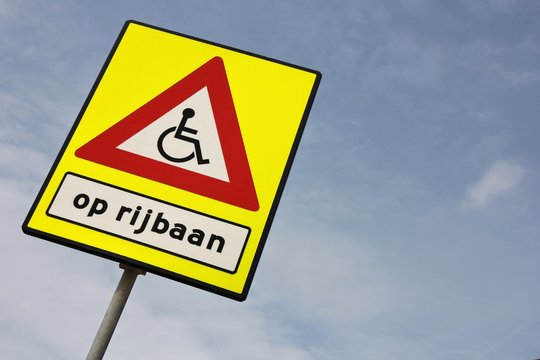 niederländisches Verkehrszeichen: Rollstuhlfahrer auf der Fahrbahn