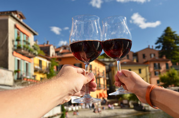 Two wineglasses in the hands. Varenna town at the lake Como, Ita
