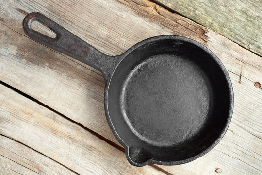 old iron frying pan on wooden rustic table
