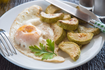 fried eggs and chopped zucchini with parsley on the plate