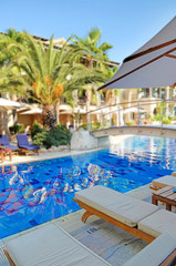 Fototapeta premium Deck chairs next to a swimming pool in an exotic location