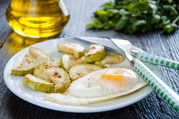 fried eggs and chopped zucchini with parsley on the plate