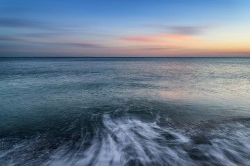 Stunning long exposure seascape image of calm ocean at sunset