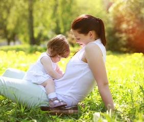 Mom and baby having fun on grass in the summer park