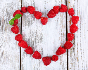 Heart shaped raspberries on wooden background